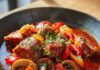 Goulash de porc aux poivrons et champignons Assiette généreuse de goulash de porc aux poivrons et champignons, nappée de sauce au paprika, servie avec du riz blanc.