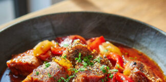Assiette généreuse de goulash de porc aux poivrons et champignons, nappée de sauce au paprika, servie avec du riz blanc.