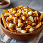 Recette de la poutine typique québécoise : frites maison, fromage en grains et sauce brune onctueuse. Une explosion de saveurs authentiques !