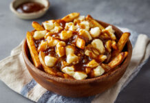 Recette de la poutine typique québécoise : frites maison, fromage en grains et sauce brune onctueuse. Une explosion de saveurs authentiques !