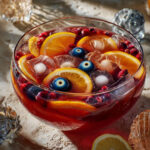 Grand saladier de punch d’Halloween rouge sang, garni de rondelles d’agrumes, fruits rouges et d’une main glacée, prêt à être servi.