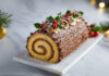 Bûche de Noël au chocolat : recette traditionnelle à la crème au beurre Bûche de Noël roulée au chocolat avec crème au beurre, décorée de houx, rosettes et sucre glace sur plat blanc.