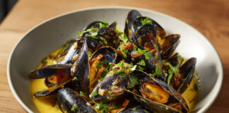 Bol de moules de bouchot nappées de sauce crémeuse au curry et au vin blanc, typique de la mouclade charentaise.