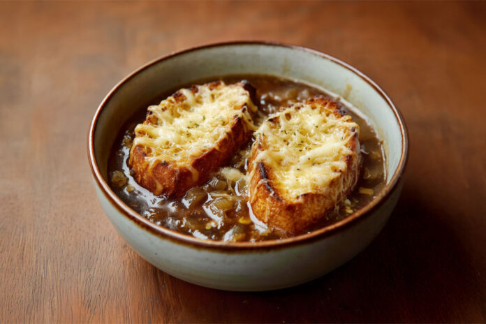 Bol de soupe à l’oignon gratinée avec tranches de pain dorées et fromage fondu – une recette française traditionnelle et réconfortante.