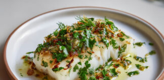 Dos de cabillaud cuit au four, nappé de citron confit haché et d’herbes fraîches, dans une sauce légère à l’huile d’olive.