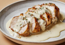 Filet mignon sauce roquefort blanche Filet mignon de porc tranché, nappé d’une sauce blanche crémeuse au roquefort, servi chaud dans une assiette rustique.