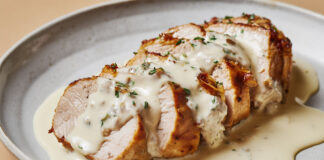 Filet mignon de porc tranché, nappé d’une sauce blanche crémeuse au roquefort, servi chaud dans une assiette rustique.