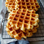 Gaufres de Bruxelles maison dorées et croustillantes, empilées sur une grille à pâtisserie, prêtes à être dégustées.