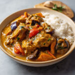 Assiette de mafé de poulet sénégalais avec carottes, aubergines et patate douce, nappée de sauce onctueuse à la pâte d’arachide, servie avec du riz blanc.