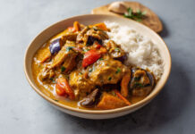 Mafé de poulet sénégalais Assiette de mafé de poulet sénégalais avec carottes, aubergines et patate douce, nappée de sauce onctueuse à la pâte d’arachide, servie avec du riz blanc.