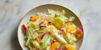 Assiette de salade d’hiver colorée aux endives, quartiers d’orange, pommes croquantes et noix, sur fond clair – recette fraîche et saine.