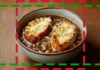 Bol de soupe à l’oignon gratinée avec tranches de pain dorées et fromage fondu – une recette française traditionnelle et réconfortante.